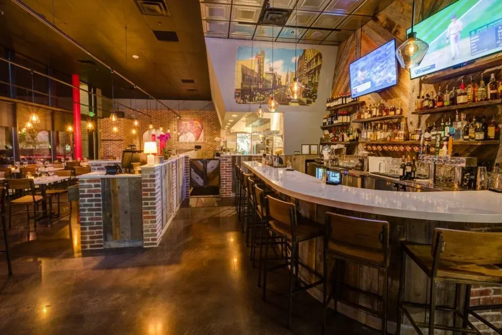 The bar at Viale Pizza & Kitchen, with reclaimed wood, exposed brick and warm pendant lighting
